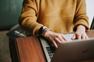 Zelfstandige typt op een laptop aan een houten bureau