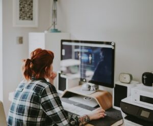 Vrouw werkt aan haar website op een thuiswerkplek met groot beeldscherm
