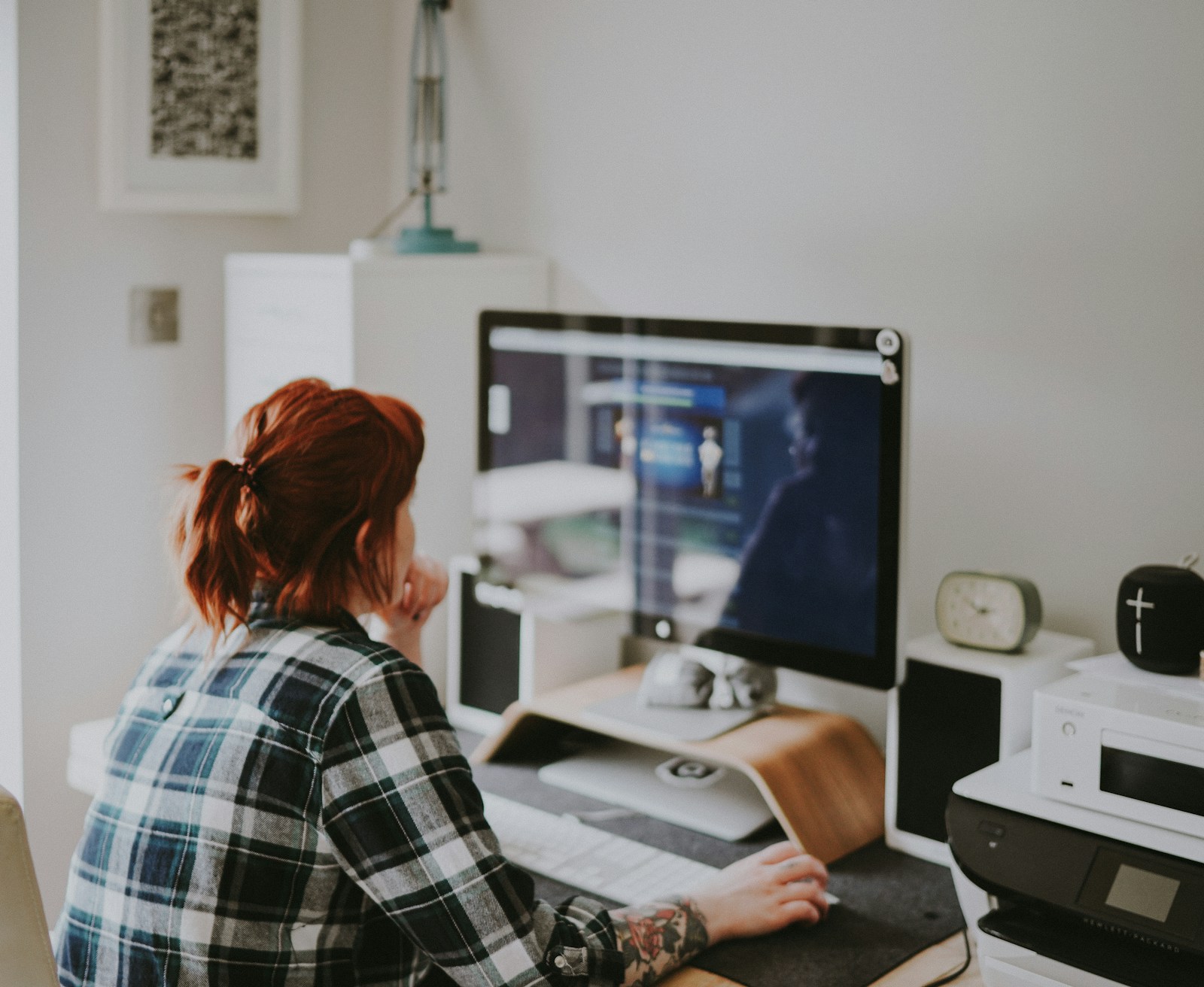 Vrouw werkt aan haar website op een thuiswerkplek met groot beeldscherm
